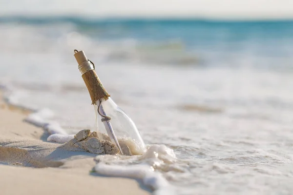 Message in the bottle washed ashore against the sun setting down. Tropical beach design background, message in the bottle washed ashore against the Sun setting down