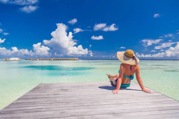Tropik plajda mavi bikinili bir kadının yaz portresi. Denizde gülümseyen genç bir kadının portresi. Mayolu esmer kız sahilde yürüyor ve eğleniyor..