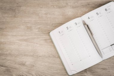 Tahta yüzey üzerinde boş defter, takvim, kalem ve akıllı telefon ile düz uzandı