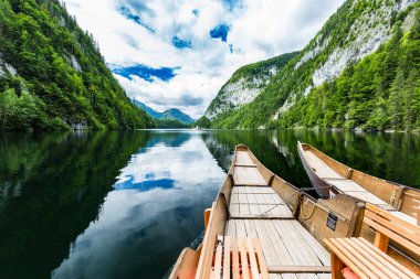 Huzurlu dağ gölündeki ahşap teknenin yakın görüntüsü. Yaz macerası geçmişi, dağlardaki yeşil ormanlı göl yansıması. Şaşırtıcı manzara, dağlık doğa.