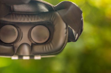 Sanal gerçeklik kulaklığı, Google. VR gözlükler, açık hava parkında çimlerin üzerinde oturan sanal gerçeklikle ekranı birbirine değdirin. VR kulaklık cihazı. Doğa arka planı. İnsanlar ve teknoloji kavramı