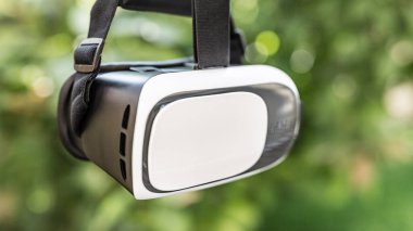 Sanal gerçeklik kulaklığı, Google. VR gözlükler, açık hava parkında çimlerin üzerinde oturan sanal gerçeklikle ekranı birbirine değdirin. VR kulaklık cihazı. Doğa arka planı. İnsanlar ve teknoloji kavramı