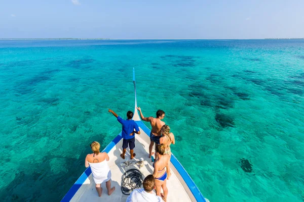 Tourist guide and tourists looking for dolphins and marine life in open sea in Maldives lagoon. Maldives traditional boat Dhoni and perfect blue sea with lagoon. Water sport, snorkel and diving, exotic tourism, people recreational activity