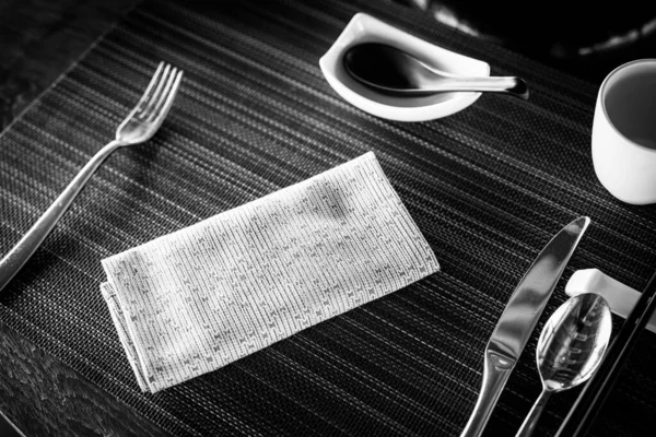 Asian dinner set. Traditional dinner set-up composition on dark background with bamboo mat, white napkin, soy sauce, copy space in black and white