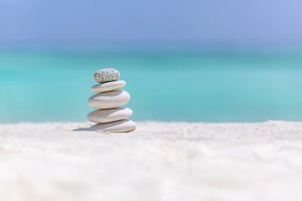 Zen stones on tropical beach for perfect meditation. Stones pyramid on soft sandy beach symbolizing stability, zen, relaxation, harmony, balance, inspirational, sea, peace. Shallow depth of field.