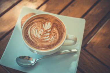 Sabah güneşi kahveli sütlü kahve sanatı. Latte sanat ve kurabiyeli beyaz kupa. Sabah havası, titreşimler, tatlı kapuçino.