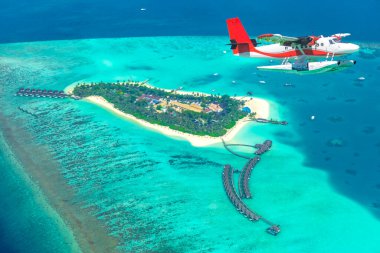 Maldivler 'deki adaya yaklaşan bir deniz uçağının hava görüntüsü. Kuş bakışı Maldivler plajı. Maldivler adasındaki hava manzarası, Ari mercan adası. Maldivler 'deki tropik adalar havadan görülebiliyor. Maldivler 'de yaz tatili plaj manzarası.