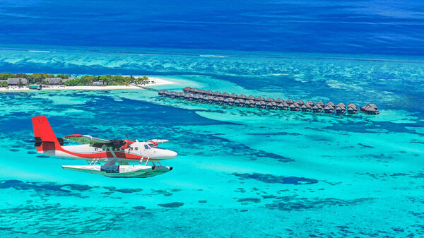 Aerial view of a seaplane approaching island in the Maldives. Maldives beach from birds eye view. Aerial view on Maldives island, Ari atoll. Tropical islands atolls in Maldives from aerial view. Summer holiday beach landscape background in Maldives.