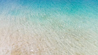 Son derece berrak mavi turkuaz bir suyun havadan görünüşü. Şeffaf turkuaz deniz suyu, doğal arka plan. Yaz ve seyahat tatil konsepti.