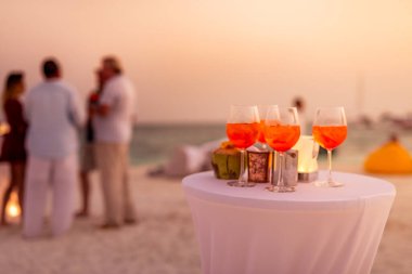Aperol spreyli kokteyl içeceği, seçici odaklanma ve detaylar. Tropik plajda alkollü içecek. Plaj partisinde aperol spreyli kokteyller ve arka planda bulanık insanlar vardı. Sığ odak içinde sosyal etkinlik karamsar afiş tasarımı