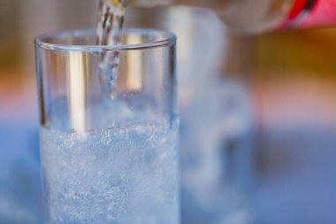 Garson cam şişeden yiyecek konseptine maden suyu döküyor. Restoranın arka planında şişeden bardağa su döken el..