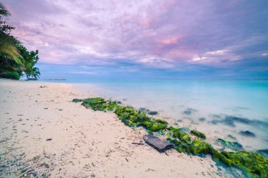 Açık mavi okyanus dalgaları üzerinde deniz yamacından tropik ada cennetini rahatlatan güzel sakin uzun pozlama. Renkli pastel günbatımı gökyüzü alacakaranlıkta. Tropik sahil günbatımı manzarası. 