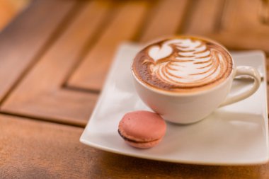 Mavi bir fincanda kapuçino ve ahşap bir masada bisküvi. Bir fincan taze kremalı kapuçino ve köpüklü latte. Eski püskü yüzeyi olan ahşap bir masa.