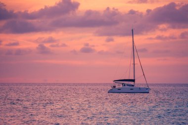 Günbatımına karşı yat sürüyor. Ufuk çizgisi yelkenli harika deniz manzaralı tatil hayatı. Yat turizmi denizcilik, cennet tatili. Günbatımında lüks bir yatta romantik bir gezi. İnanılmaz yaz tatili ulaşım konsepti