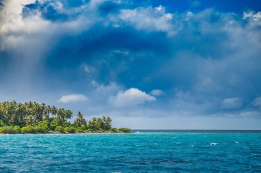 Deniz ve ada üzerinde fırtınalı bir gökyüzü. Tropik cennet manzarası, palmiye ağaçları