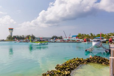 Erkek, Maldivler 10 Mayıs 2019: TMA - Maldivler 'deki MLE havaalanında Trans Maldivian Airways Twin Otter deniz uçakları. Yüzen ahşap iskelenin yanına deniz uçağı parkı, Maldivler