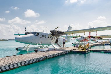 Erkek, Maldivler 10 Mayıs 2019: TMA - Maldivler 'deki MLE havaalanında Trans Maldivian Airways Twin Otter deniz uçakları. Yüzen ahşap iskelenin yanına deniz uçağı parkı, Maldivler