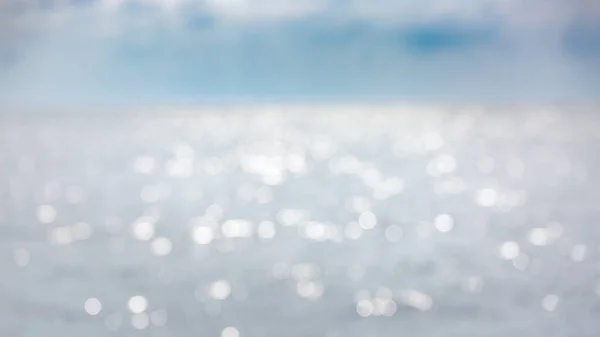 Abstract blur light on sea and ocean background for summer season. Blurred background from reflection of blue water in the river. Bokeh like main object. Wallpaper or postcard