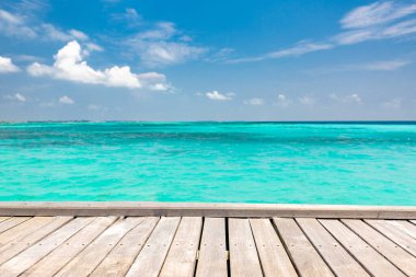 Bulanık plaj arka planında ahşap masa üstü, yaz konsepti. Tahta masa ürünü sergisi, yaz tatili, tropik bir plajın tatil geçmişi, mavi deniz, beyaz bulutlar, güneş parlaması. 