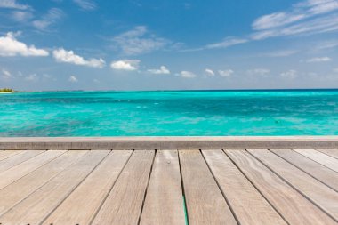 Bulanık plaj arka planında ahşap masa üstü, yaz konsepti. Tahta masa ürünü sergisi, yaz tatili, tropik bir plajın tatil geçmişi, mavi deniz, beyaz bulutlar, güneş parlaması. 