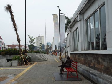 Jakarta, Endonezya - 7 Ağustos 2018: Sanat yüklemesini Kota Tua bankta oturan bir adam.