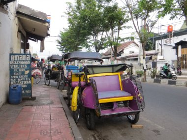 Yogyakarta, Endonezya - 31 Ekim 2018: Birkaç becak yolcular için bekleyen sokakta park edilmiş. 