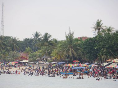 Anyer, Endonezya - 24 Haziran 2018: Kalabalık insan faaliyetleri Sambolo Plajı'nda yapıyor. Öğrencilerin uzun bir tatil gelince en yoğun Tatil Sezon Haziran ayıdır.