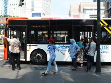 Jakarta, Endonezya - 17 Nisan 2019: Bazı yolcular Thamrin caddesindeki otobüs durağında Metrotrans otobüsünden iniyor.