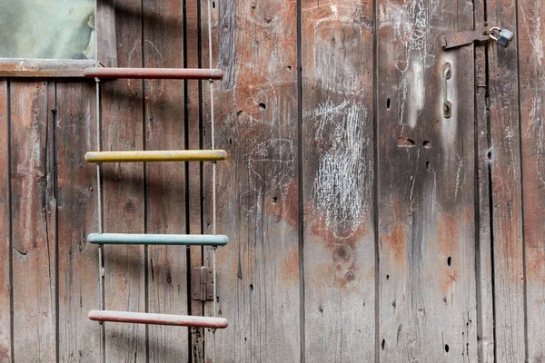Old children's rope ladder against a written wooden wall