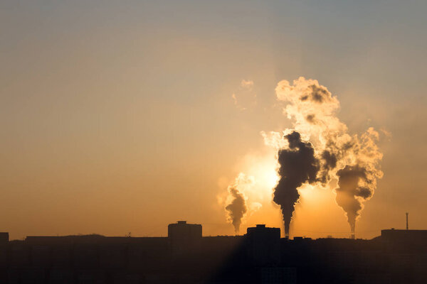 Sunrise's rays of light struggle through the smoke of factory