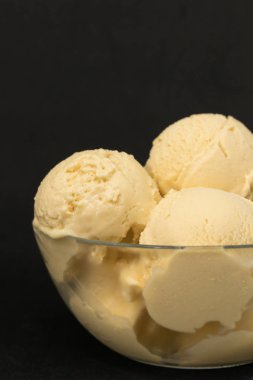 Siyah bir arka plan ve yeşil bitki üzerinde bir cam berrak derin plaka sarı ev yapımı mango dondurma