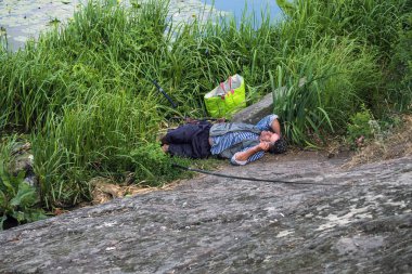 Vinnitsa, Ukrayna - 10 Haziran 2018: Sarhoş balıkçı yeleği elinde sigarayla sazlık içinde uykuya daldı