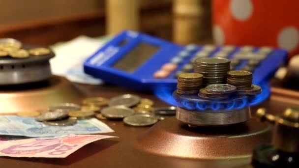 成堆的硬币站在点燃的燃气燃烧器的火焰中 在背景硬币 纸币和计算器 — 图库视频影像