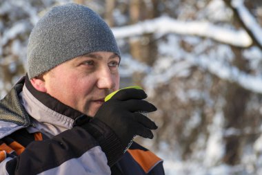 Bir fincan sıcak çay kış ormanda tutan adam