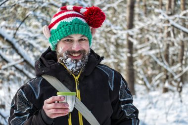 Bir fincan sıcak çay tutarak ve gülüyor kar sakallı Noel elf