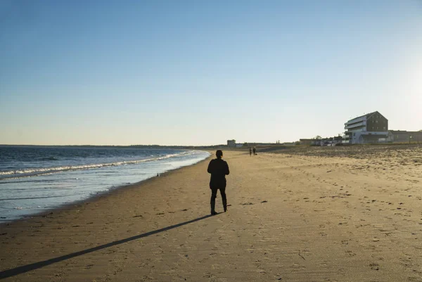 solitary old man walking on the beach