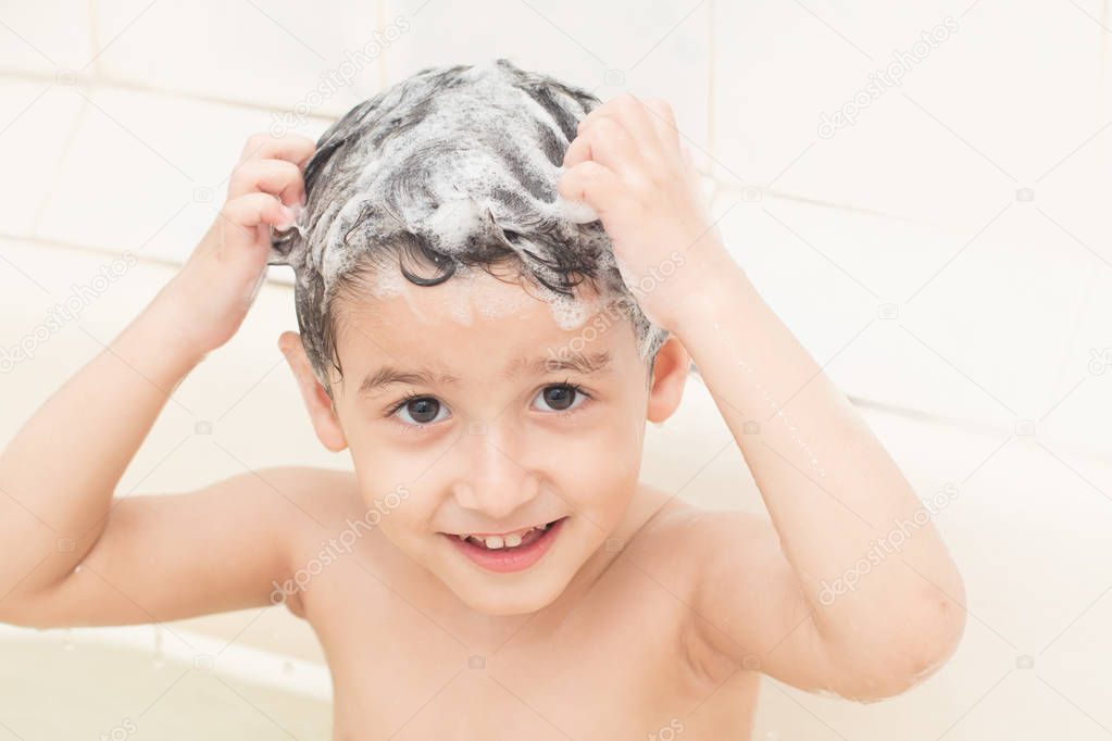 dark-haired boy washes his head with shampoo