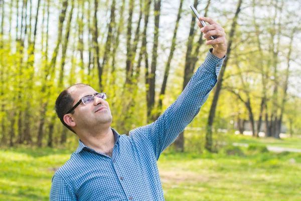 mavi gömlekli genç adam ormanın arka planda kendini bir resim alır