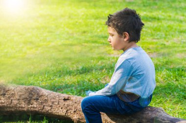 Üzgün çocuk tek başına bir günlüğüne çayır üzerinde oturmak