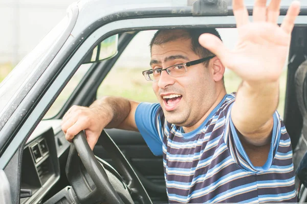 young driver in glasses emotionally reacts to passing cars