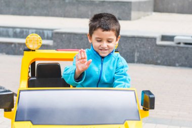 esmer çocuk parkta bir elektrikli sarı araba sürmek