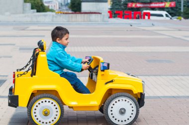 esmer çocuk parkta bir elektrikli sarı araba sürmek