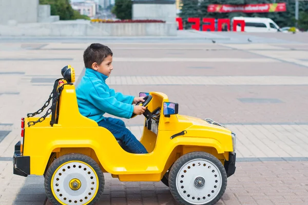 Morena Chico Monta Coche Eléctrico Amarillo Parque —  Fotos de Stock