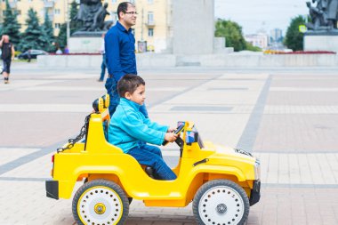 esmer çocuk parkta bir elektrikli sarı araba sürmek