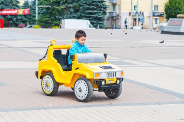 esmer çocuk parkta bir elektrikli sarı araba sürmek