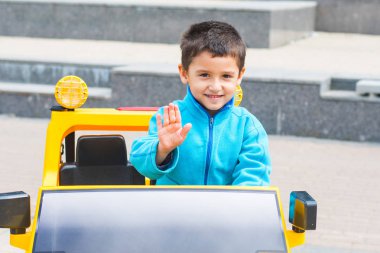 esmer çocuk parkta bir elektrikli sarı araba sürmek