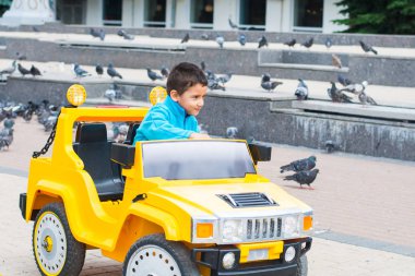 esmer çocuk parkta bir elektrikli sarı araba sürmek