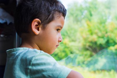 esmer çocuk tren penceresinden üzgün görünüyor