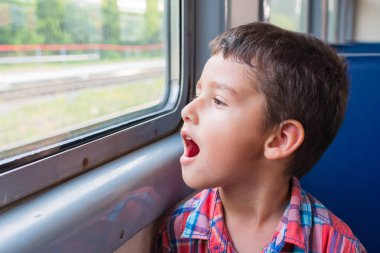 esmer çocuk tren pencerede ilgi ile görünüyor.