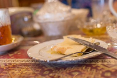 Masaya servis kahvaltı. Masada iki boş tabak. Çay yarı sarhoş